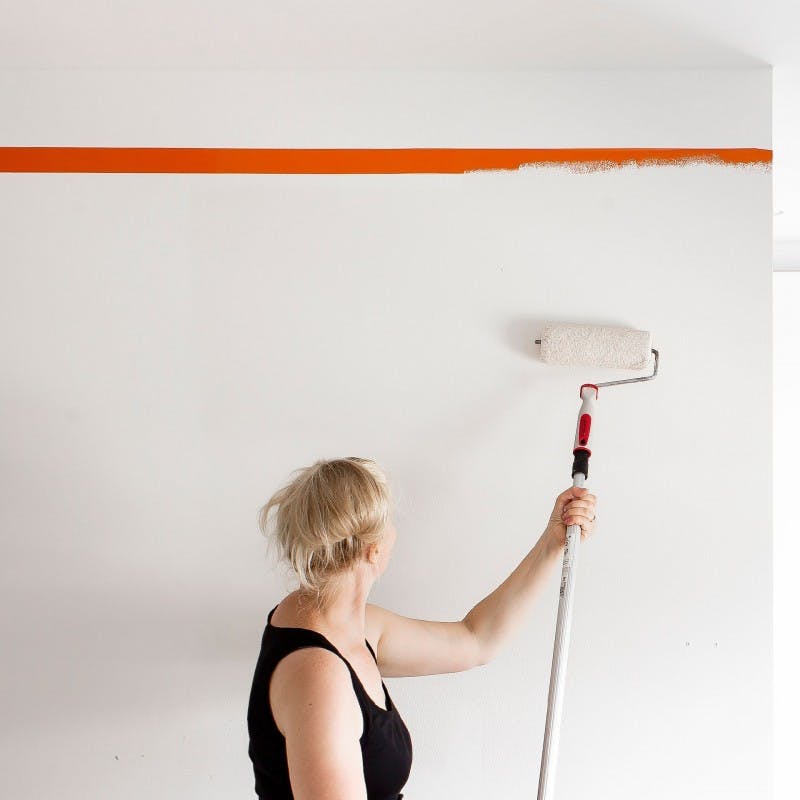 Woman with Blonde Hair Painting Wall White with Roller