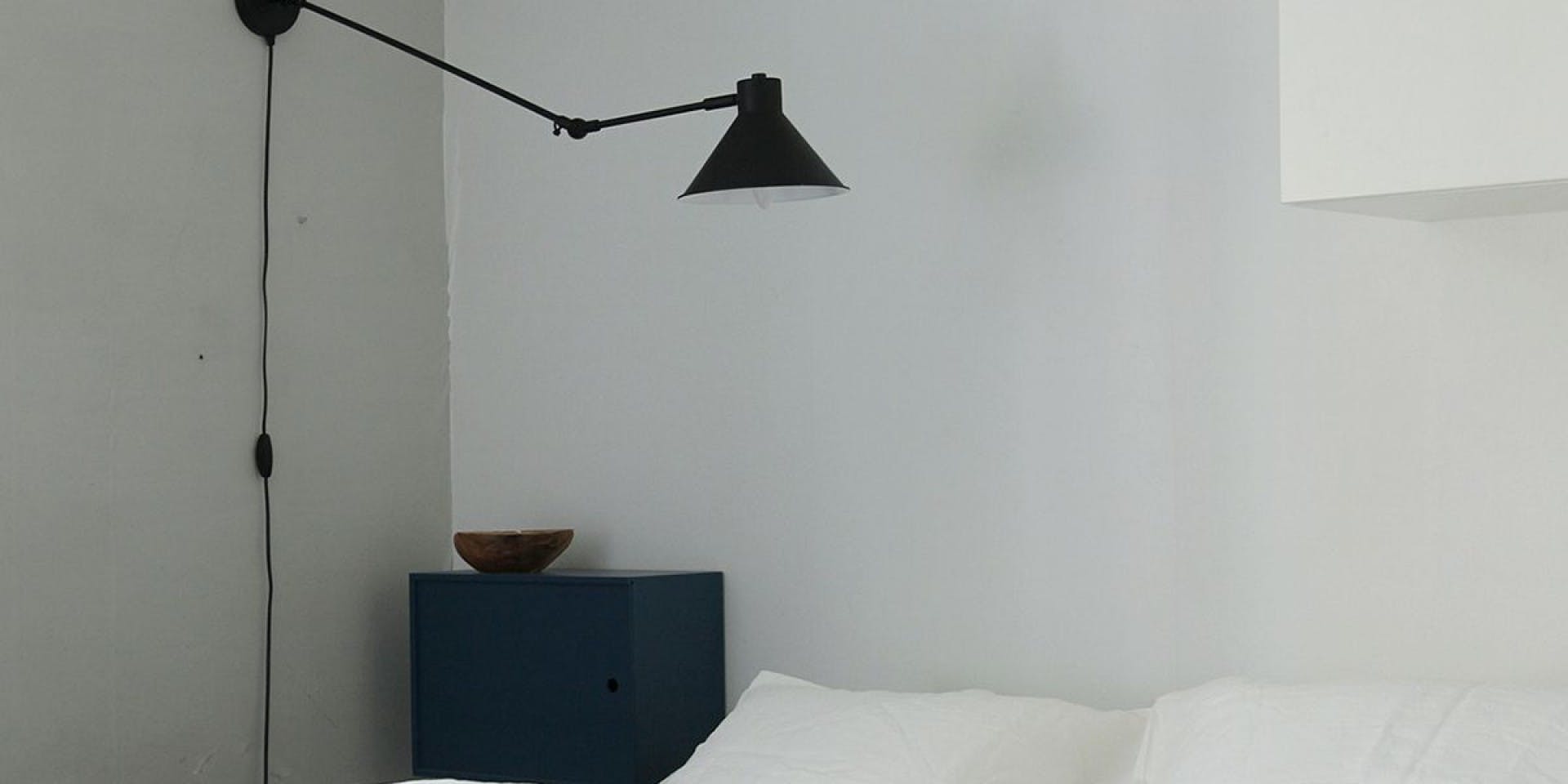 White Bedding Against Light Grey Wall, Black Side Cabinet and Black Lamp