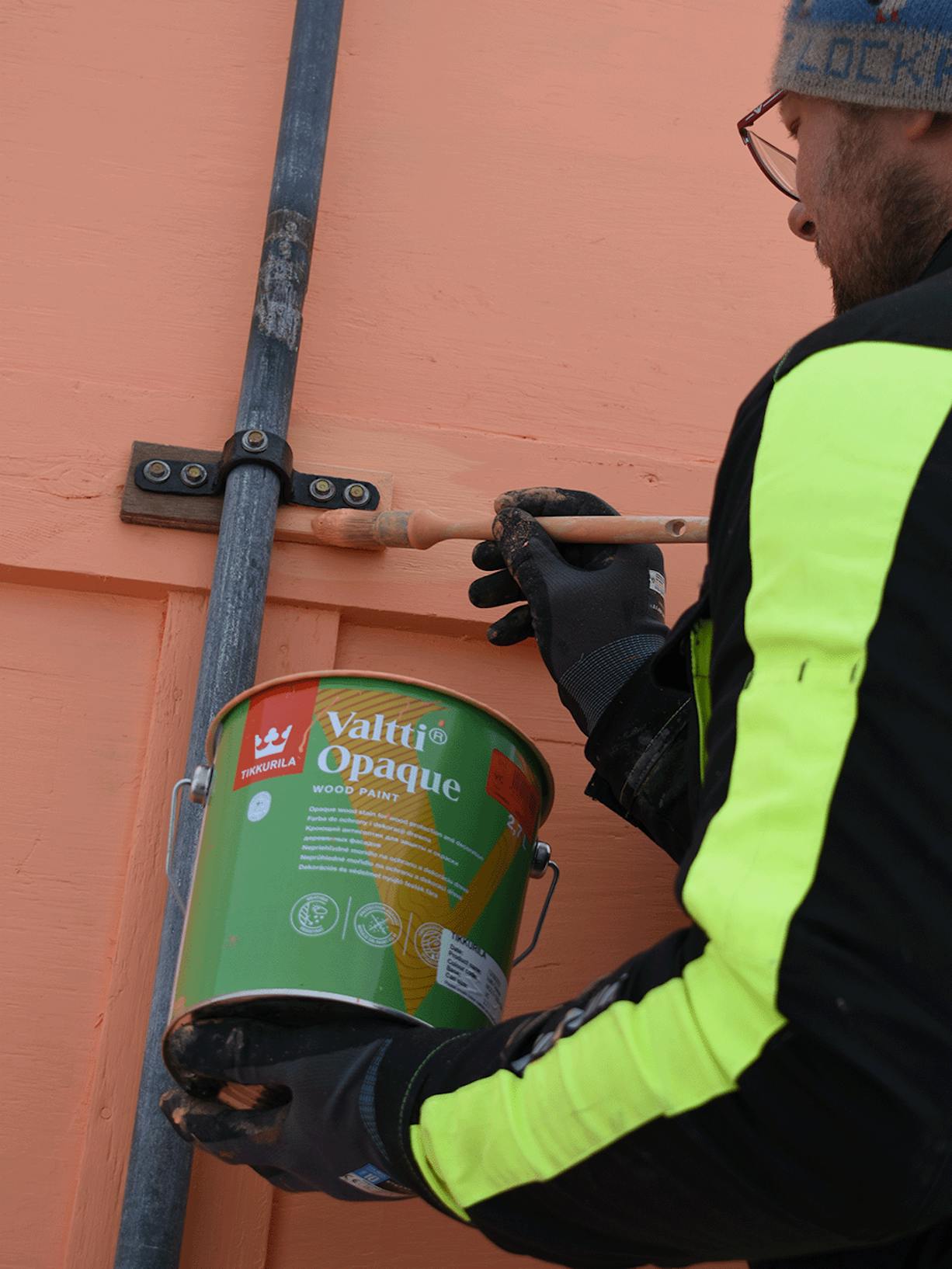 man painting wooden surface with valtti opaque paint in orange colour