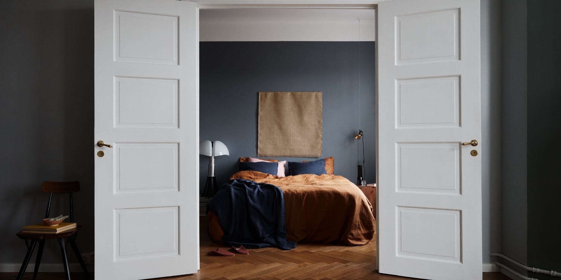 White Open Double Doors with Deep Blue Walls and Bed Behind Them