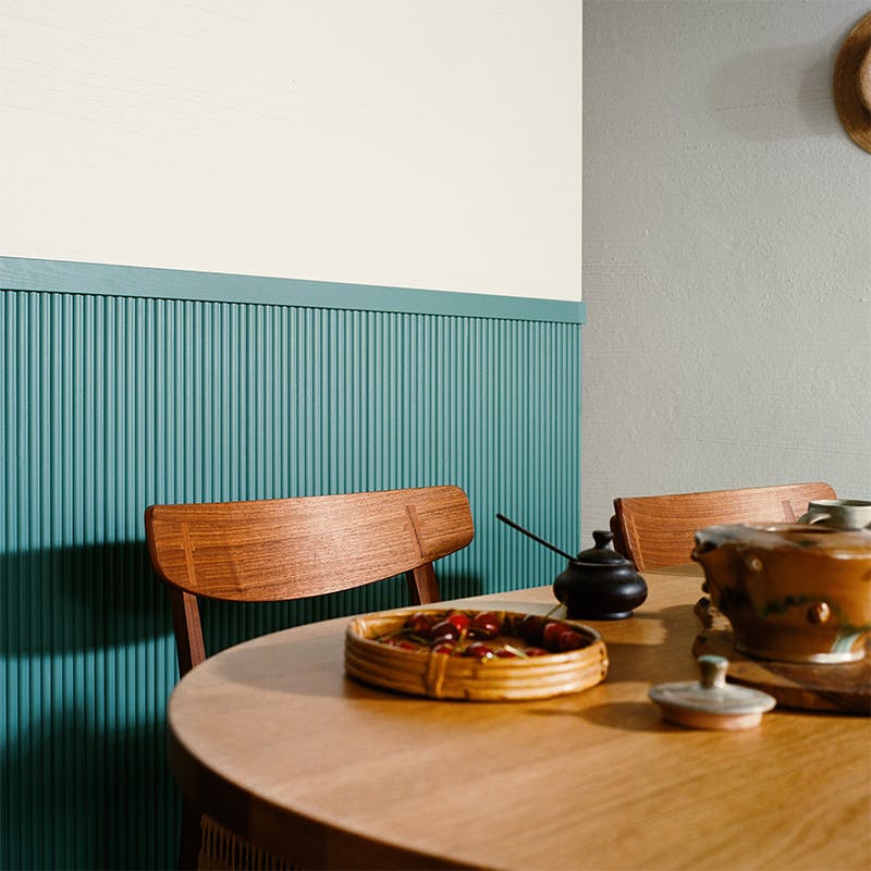 wooden table and chair in front of blue panelling 