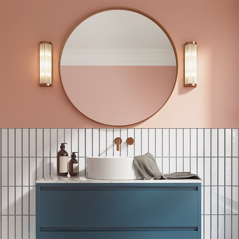 bathroom mirror and blue cabinet against pink wall