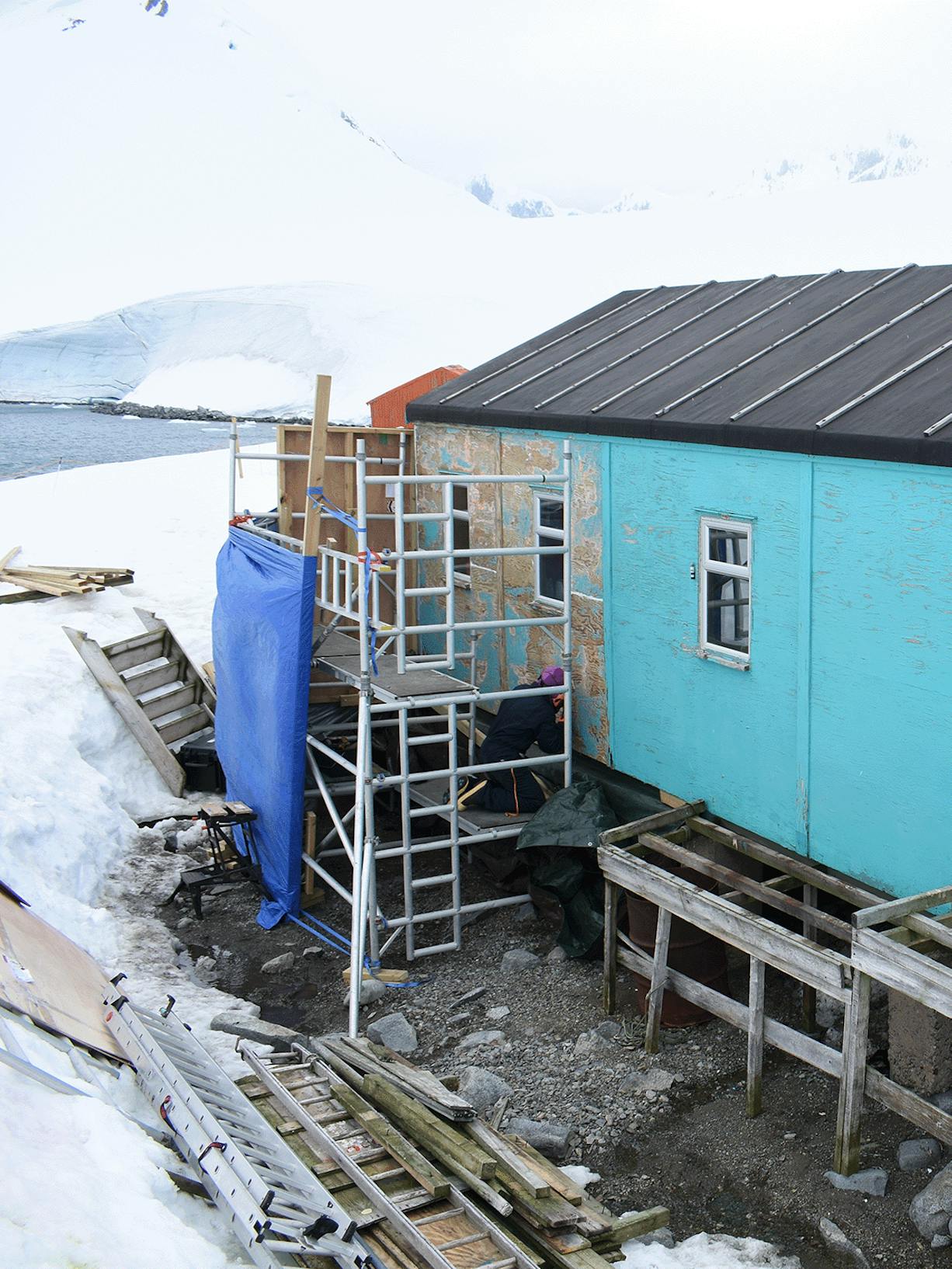 scaffolding on blue wooden hut surrounded by snow