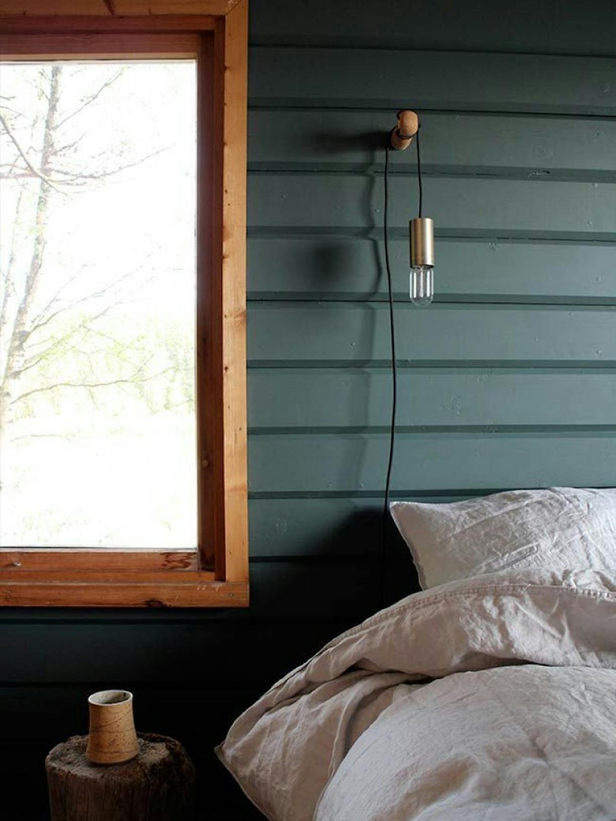 Bedroom with Dark Green Wooden Walls, Window and Bed