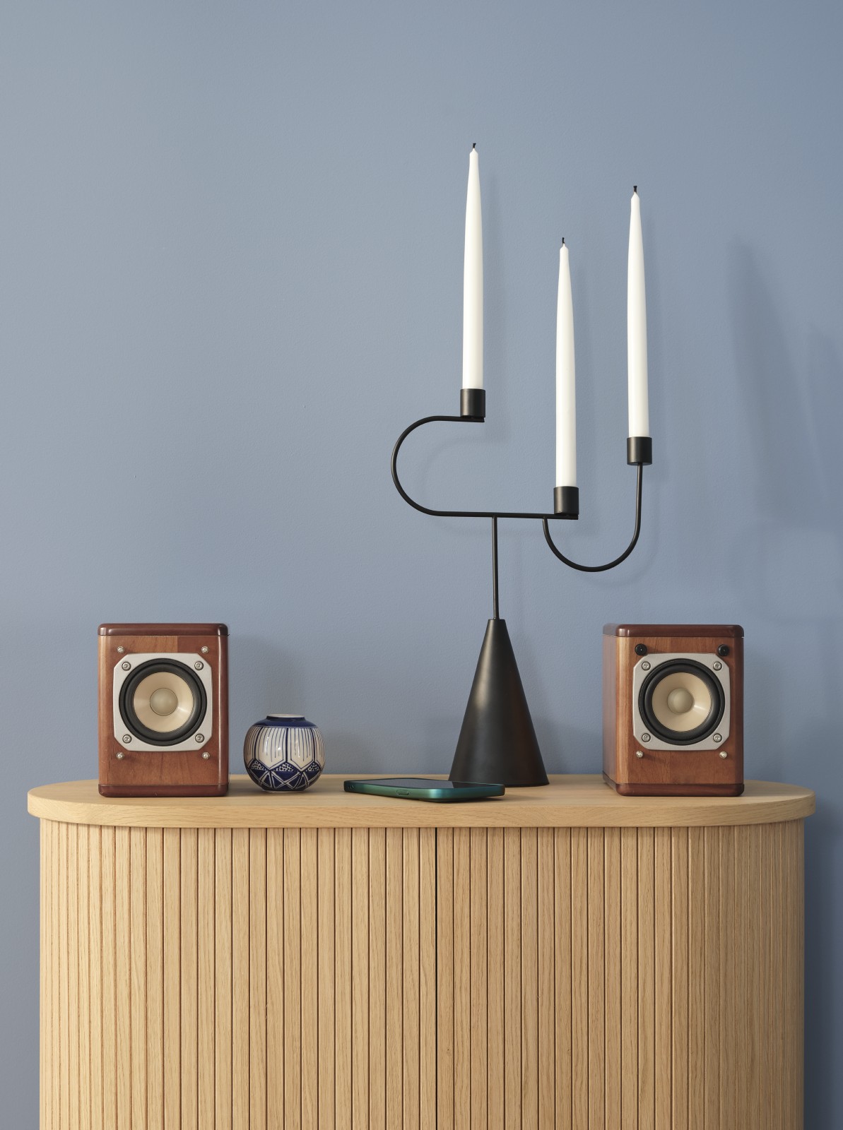 wooden cabinet with candle holder and speakers against blue wall painted in sandman v431