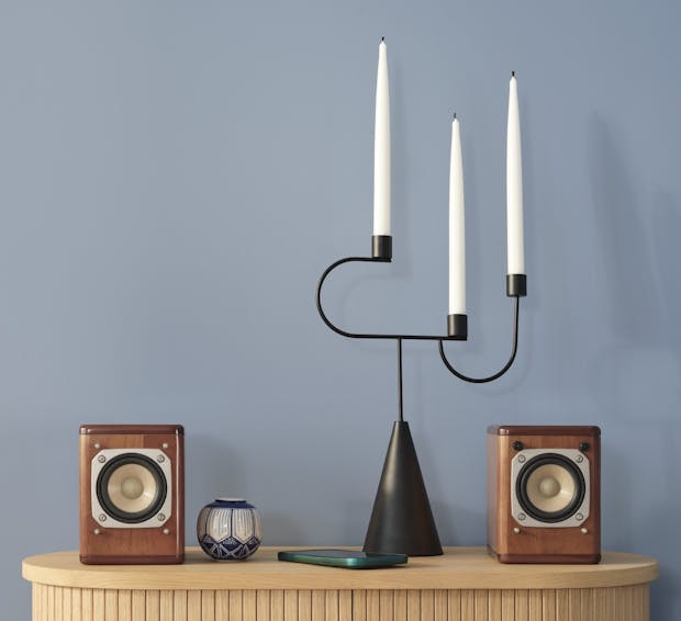 wooden cabinet with candle holder and speakers against blue wall painted in sandman v431