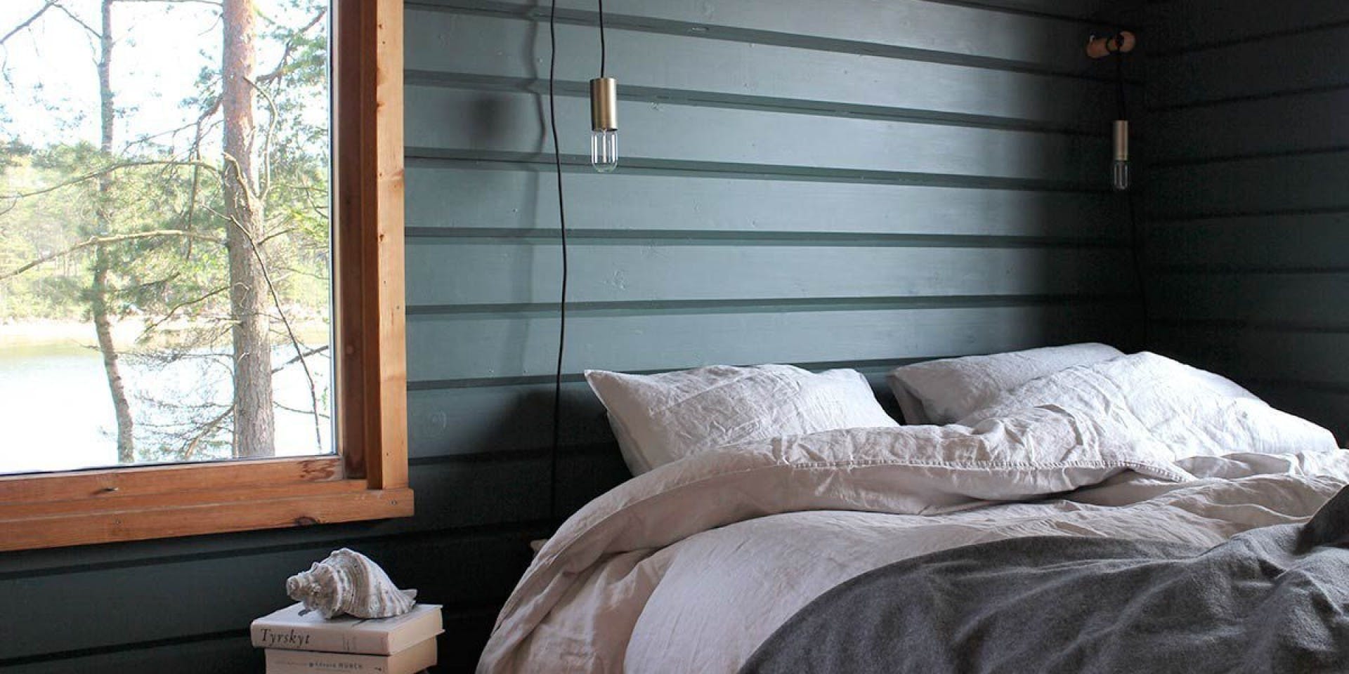 Bedroom with Dark Green Wooden Walls, Window and Bed