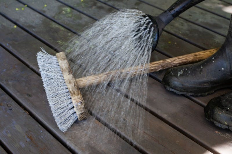 Cleaning Sweeping Brush With Water on Dark Brown Wooden Decking