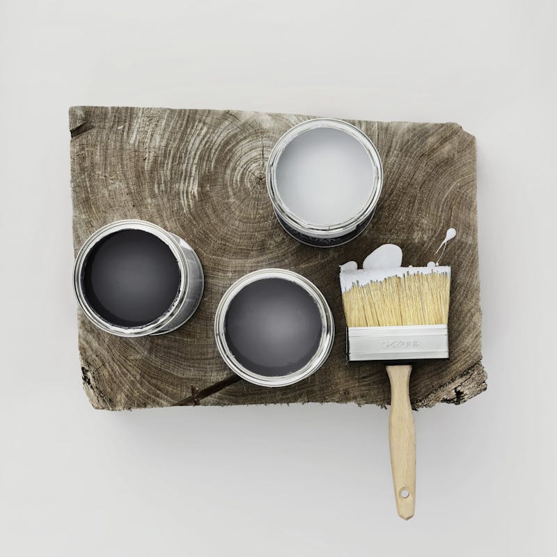 Three Open Grey Paint Tins and Paintbrush