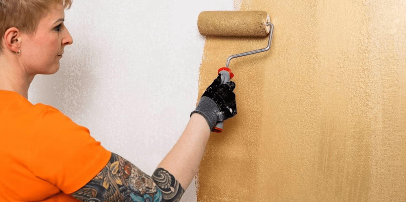 woman painting gold paint on wall