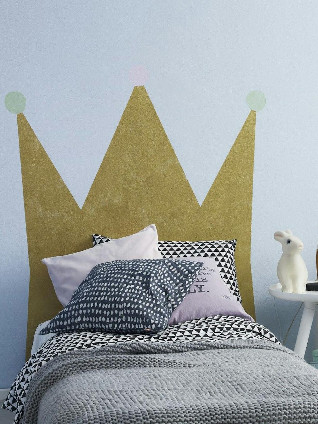 gold painted crown decoration above kid's bed