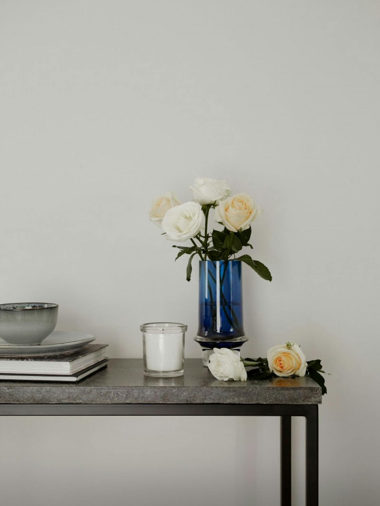 Grey Table with Blue Vase and Flowers Against White Wall