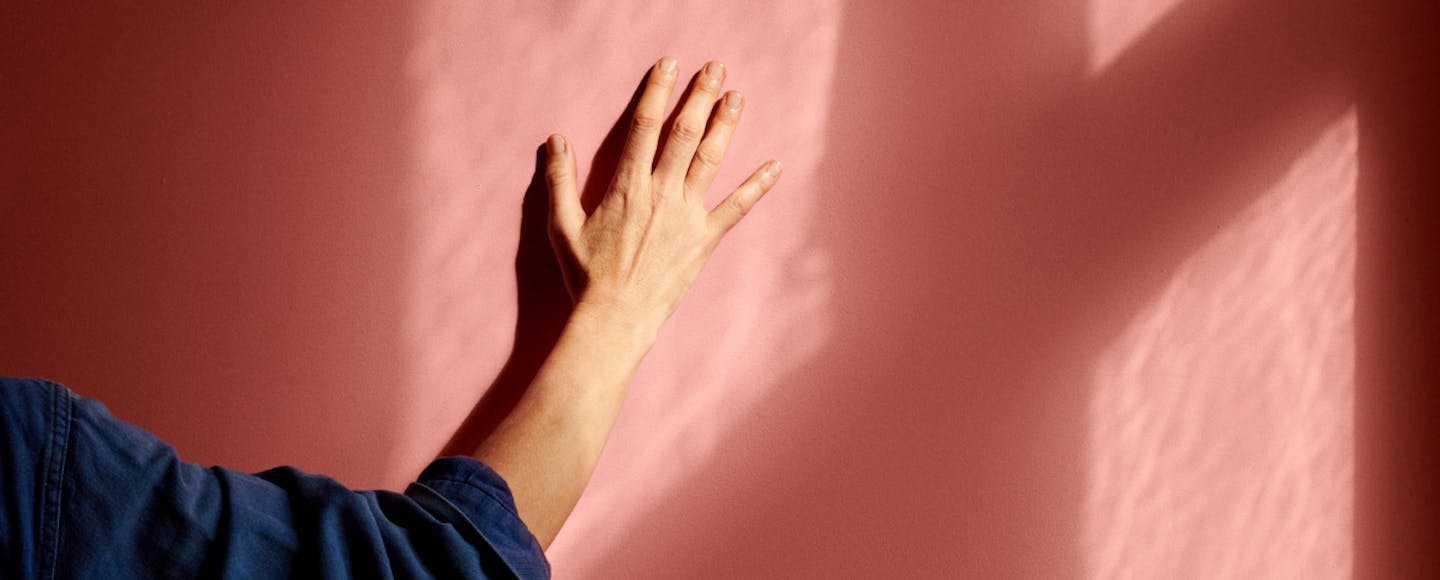 Hand touching a pink wall
