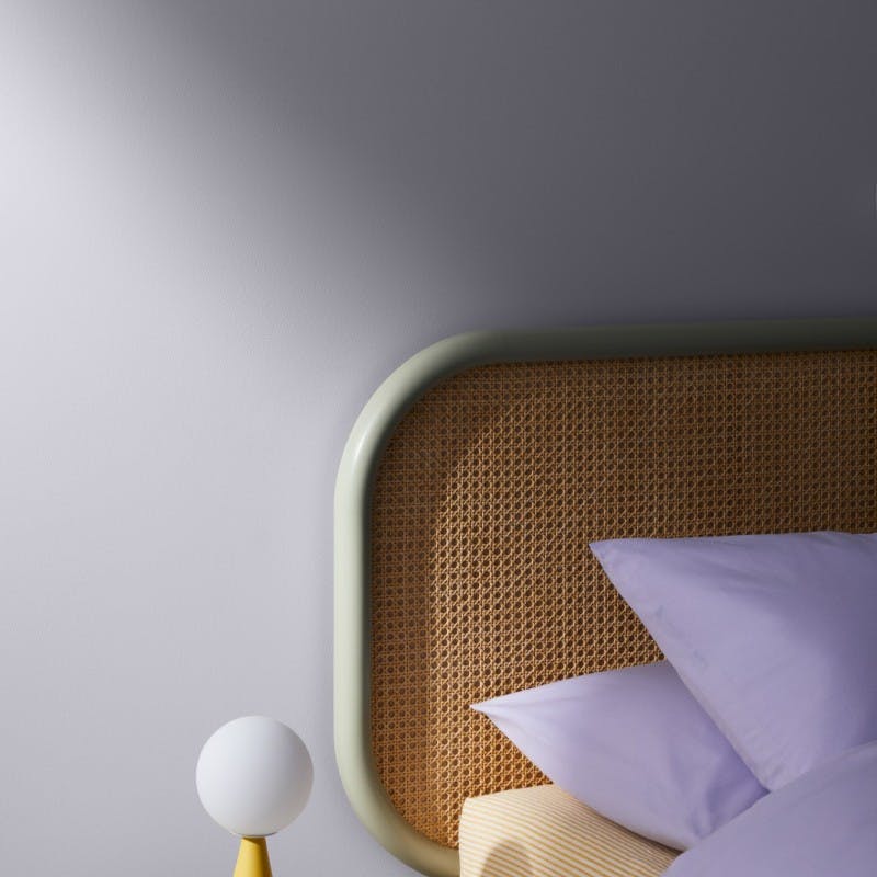 close up view of bed against light purple wall