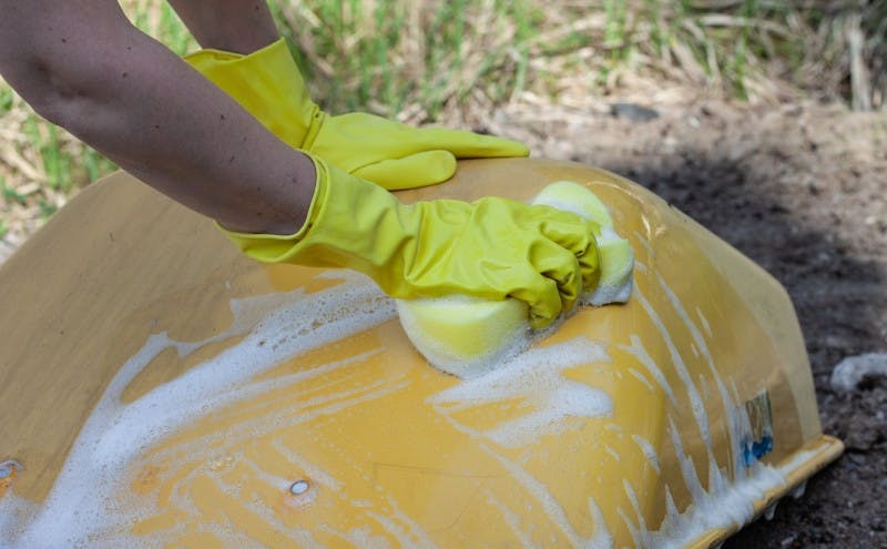 Cleaning Yellow Wheelbarrow With Soap and Sponge