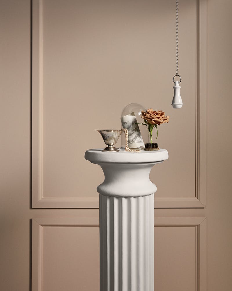 White Pillar with Decorations Against Paneled Beige Wall