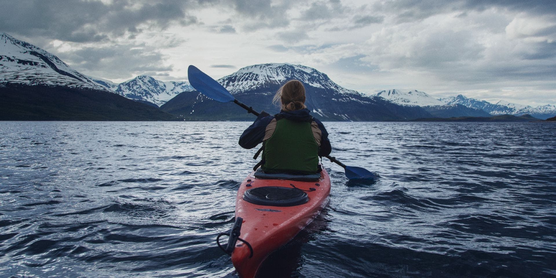 Tikkurila UK Sustainability Header Image | Man on a Red Kayak Looking at Mountains