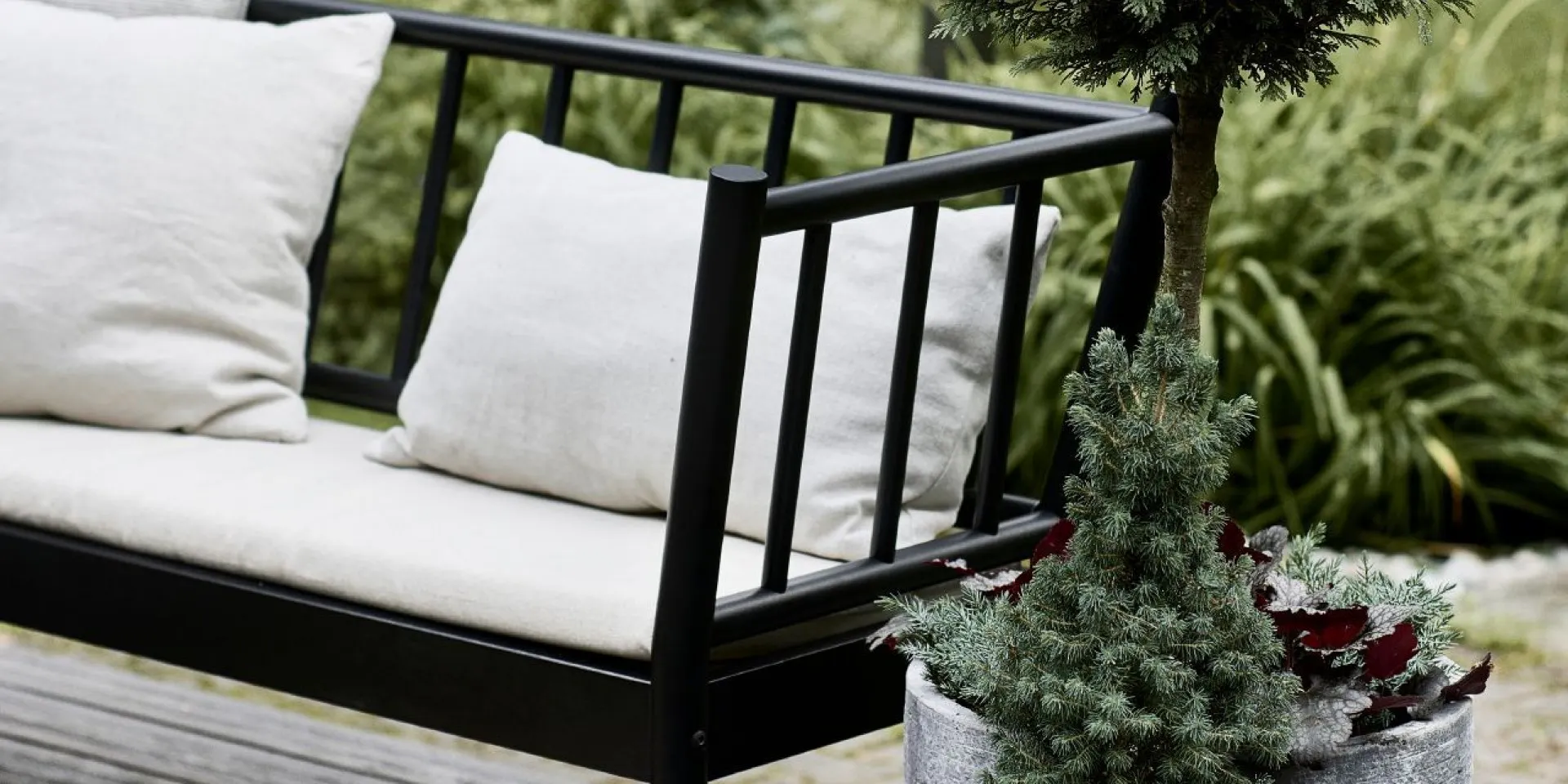 Black Garden Couch with White Pillows Surrounded with Plants