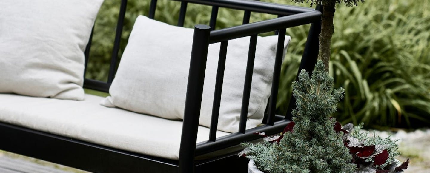 Black Garden Couch with White Pillows Surrounded with Plants
