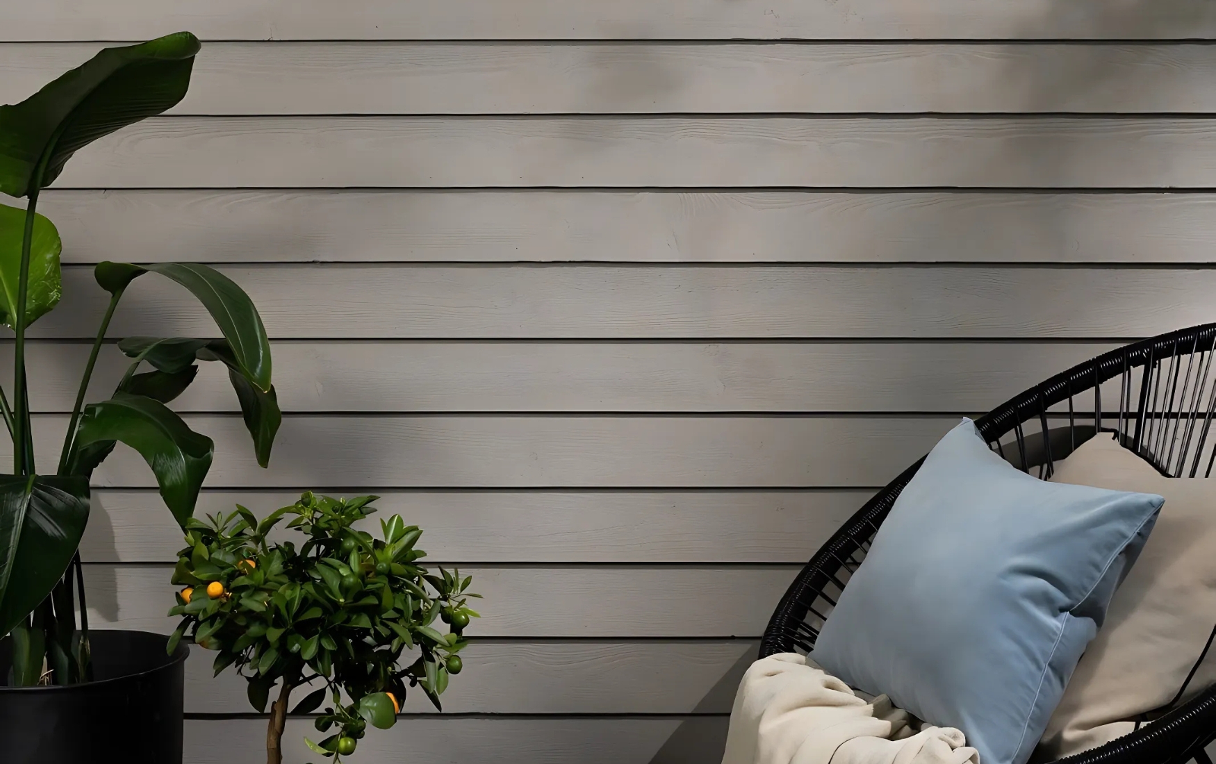 garden shed painted light grey with plant and chair in front