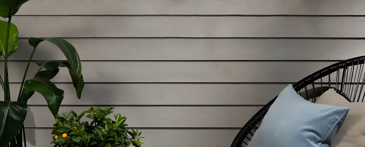 garden shed painted light grey with plant and chair in front