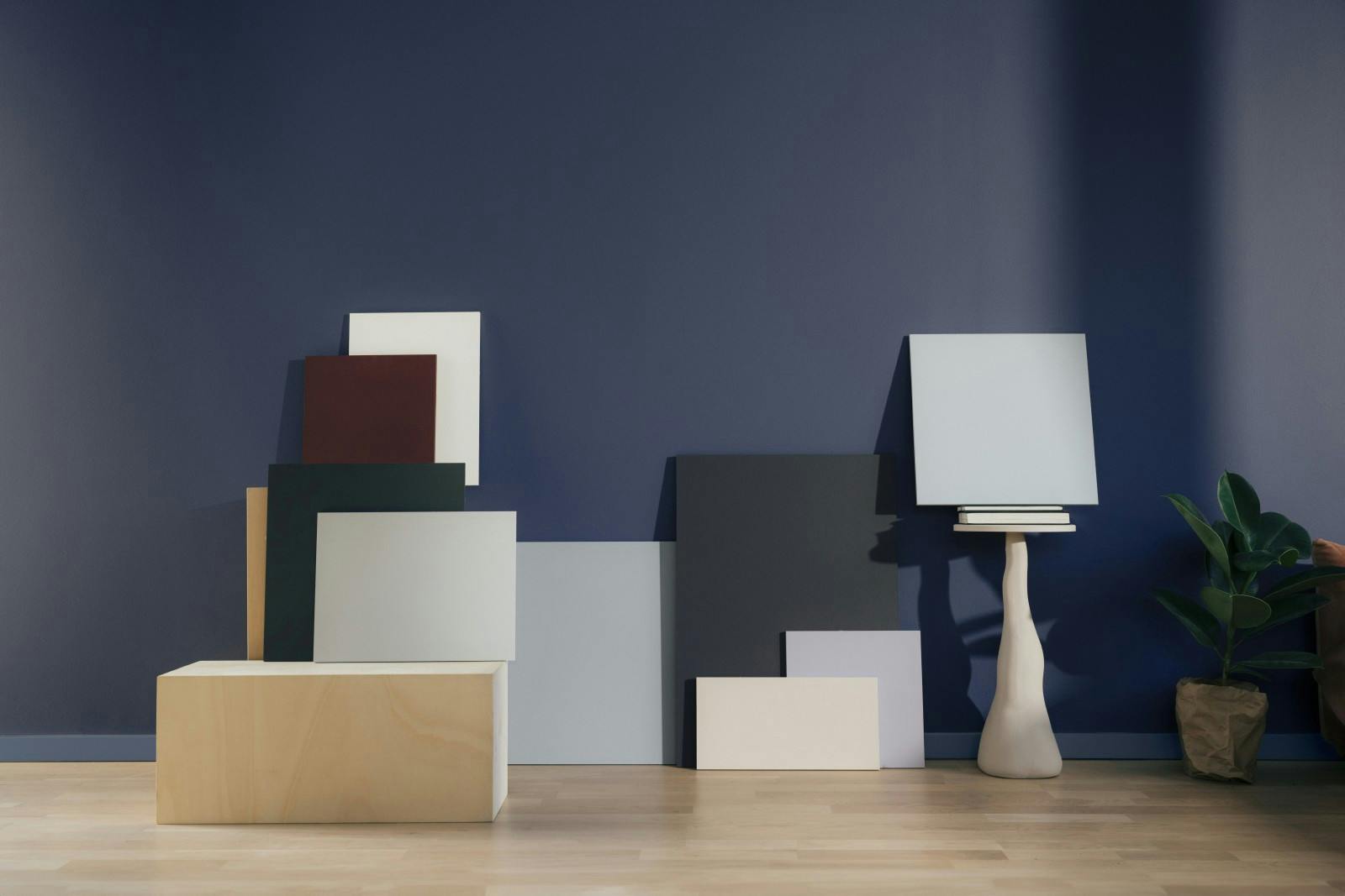 display of painted plinths in variety of colours leaning against painted dark navy wall