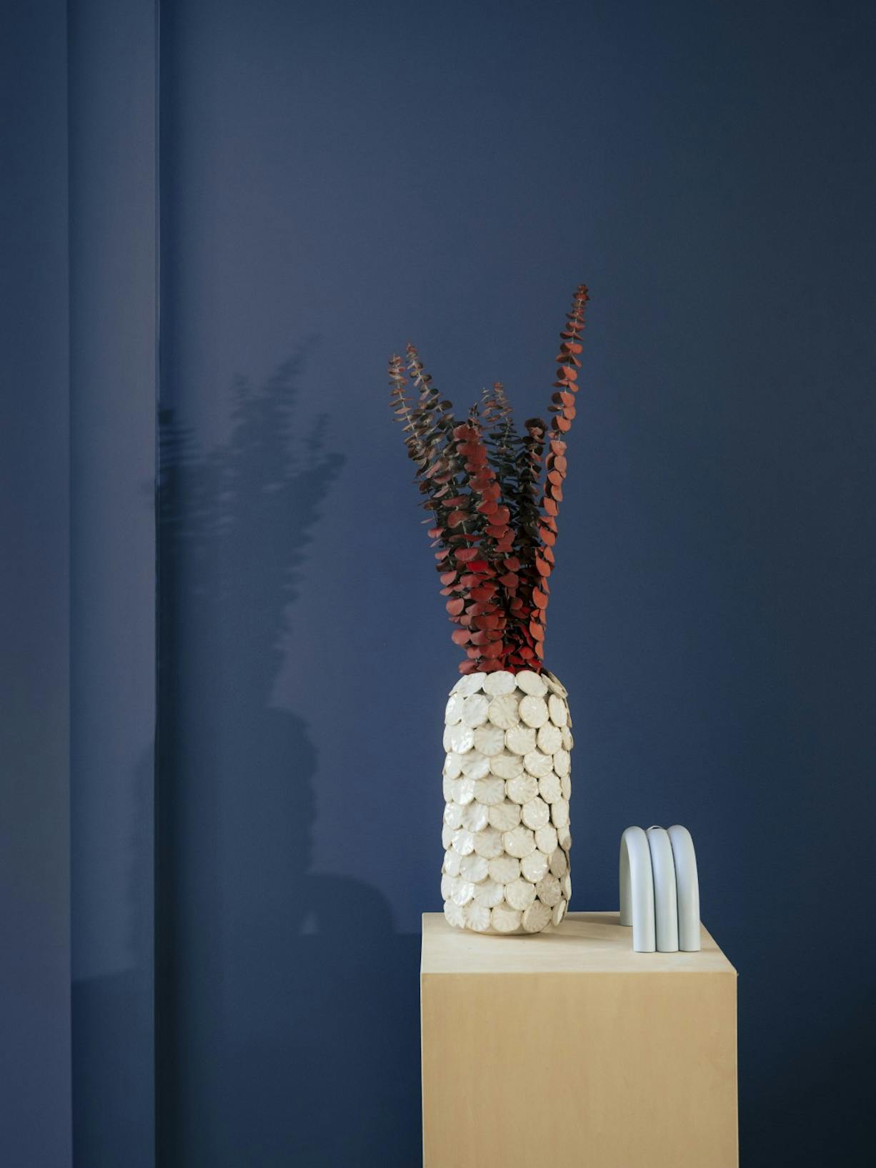 dark navy painted background with vase on plinth in foreground