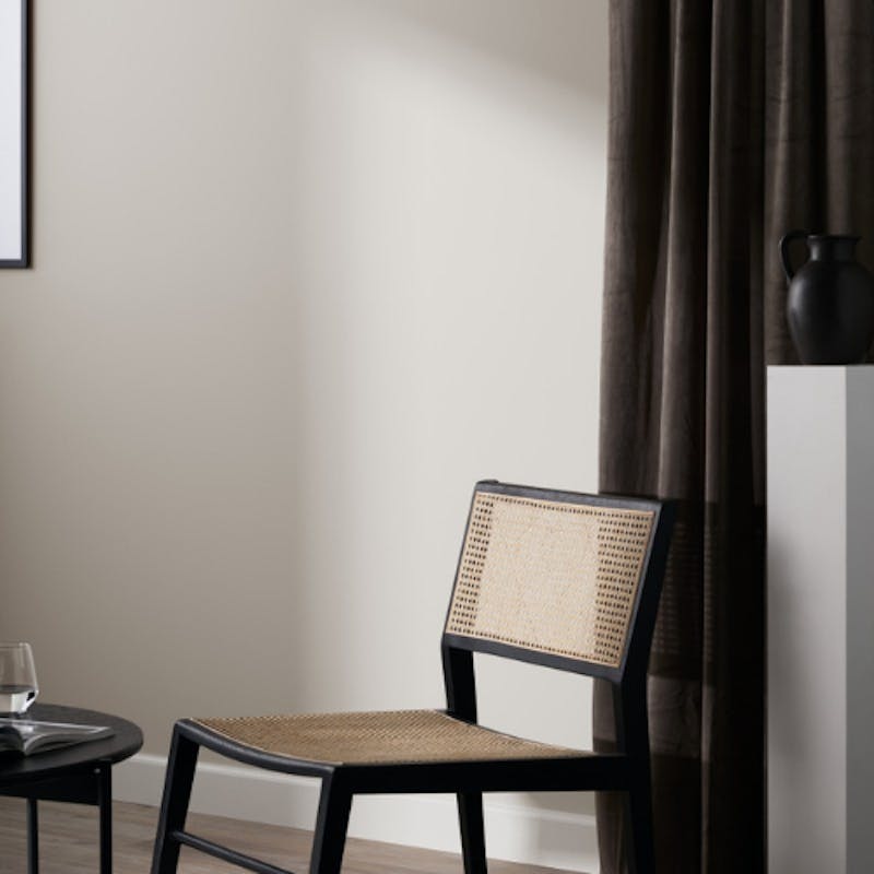 living room painted in off white neutral shade with black chair and black curtains
