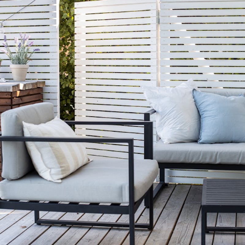 white painted garden fence with outdoor chairs in front