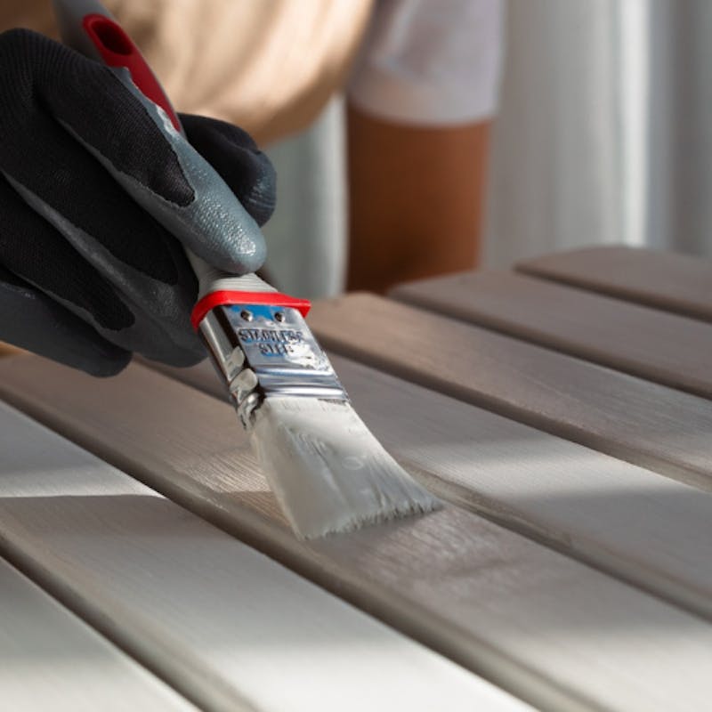 close up of decorator painting a wooden surface in light grey shade