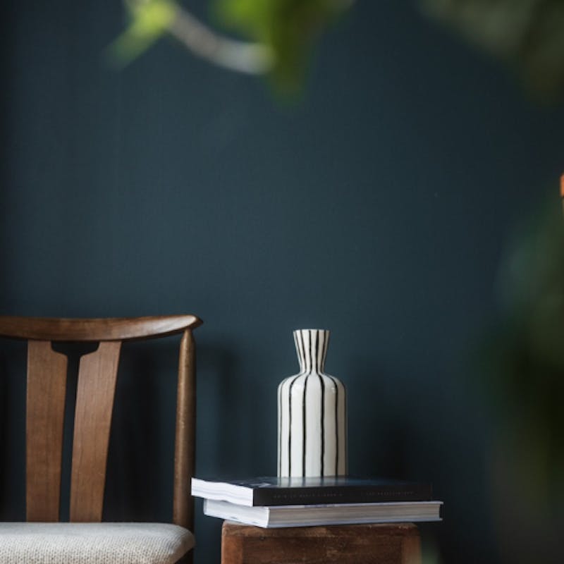 wall painted in a deep blue shade with a dark oak chair and table in front