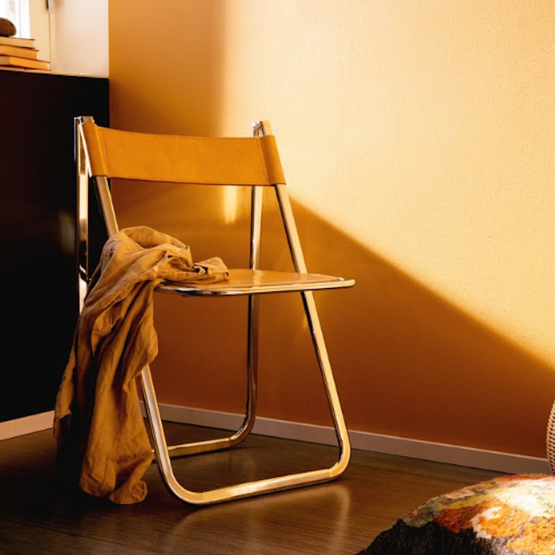yellow wall with a metal chair in front