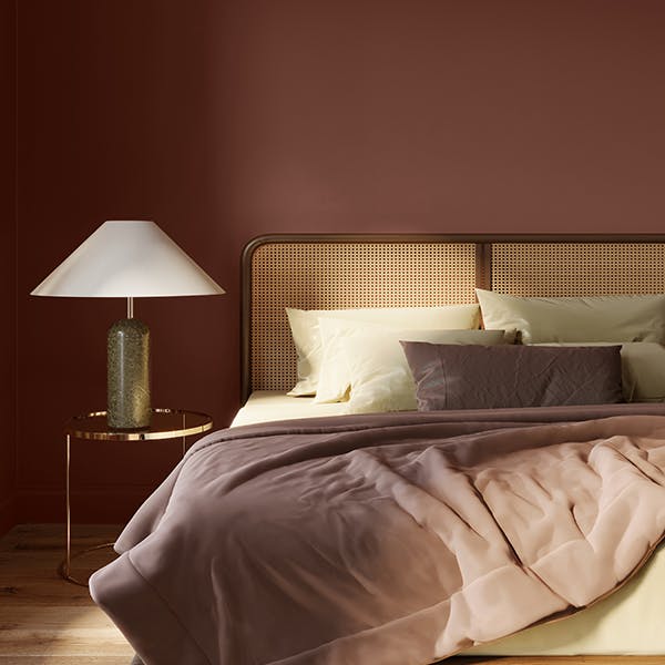 bed and side lamp in front of red brown wall