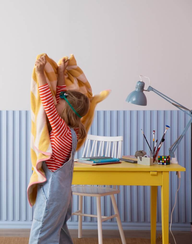 Small child playing in front of grey and blue wall