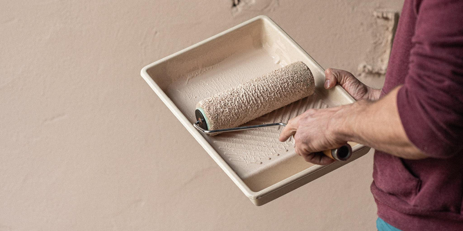 Person painting with roller and tray