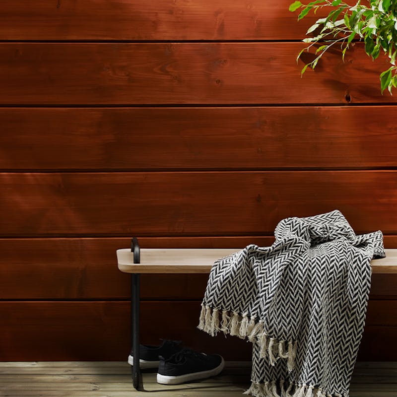 Bench and blanket in front of deep red wooden wall