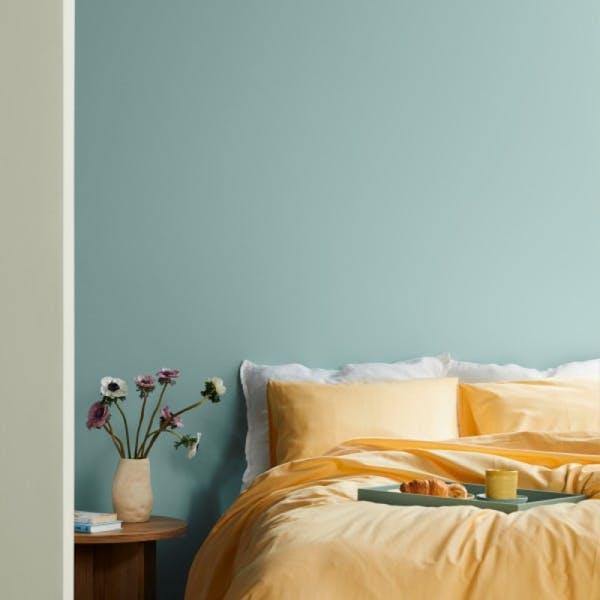 yellow bed against blue green wall painted in wave h440