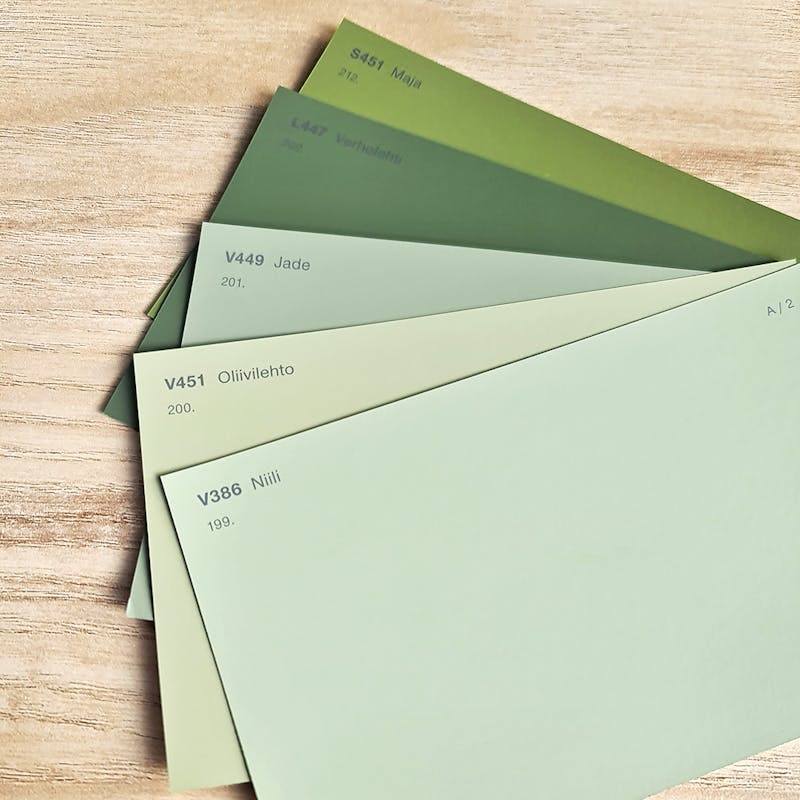 Selection of green paint colour chips on light wood