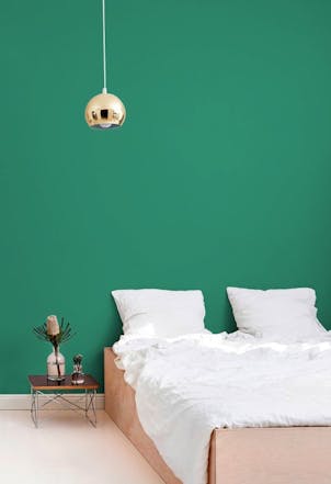A bedroom with a deep emerald green wall 