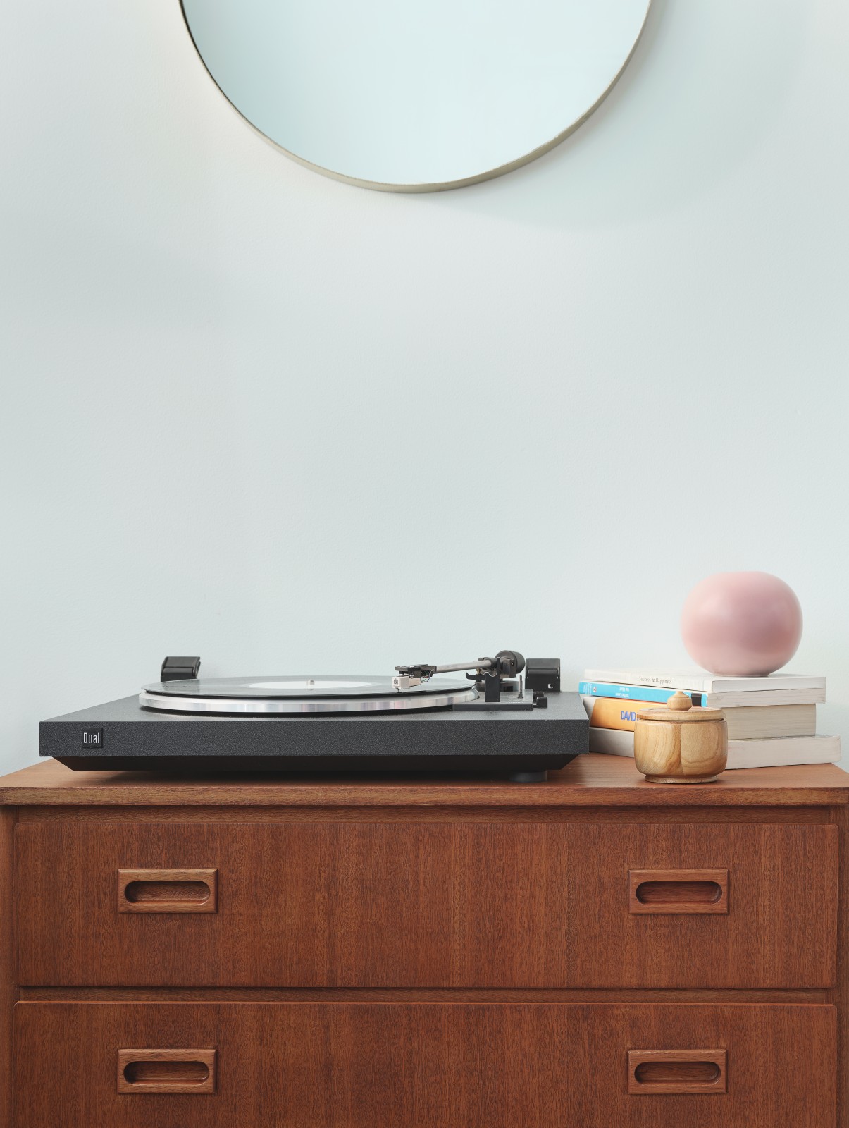Close up view of wooden cabinet and record player against light green wall painted in shade crystal g371
