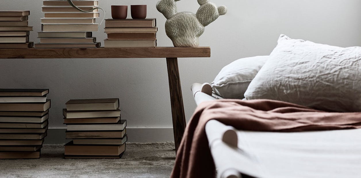 Linen Bedding and Stacks of Books on the Floor and Wooden Side Table