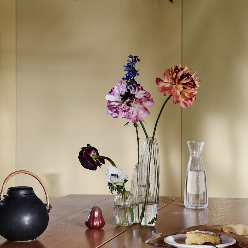 Wooden Table with Flower Vase on Top Against Yellow Wall