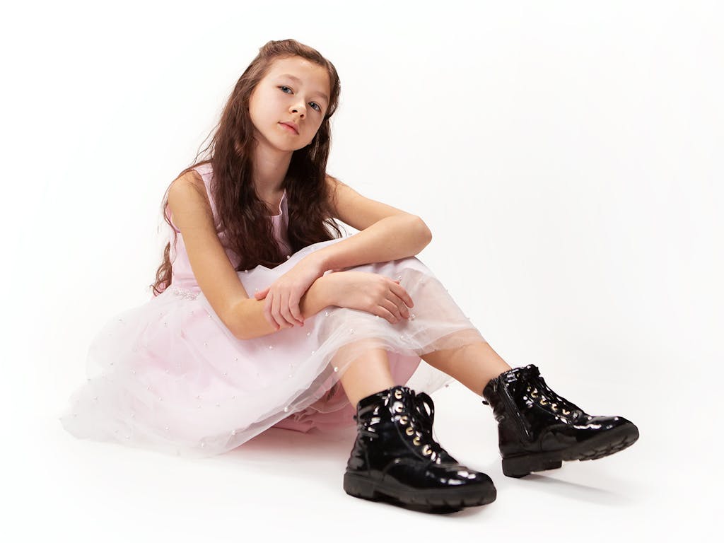 Young girl models a pink party dress and shiny black boots
