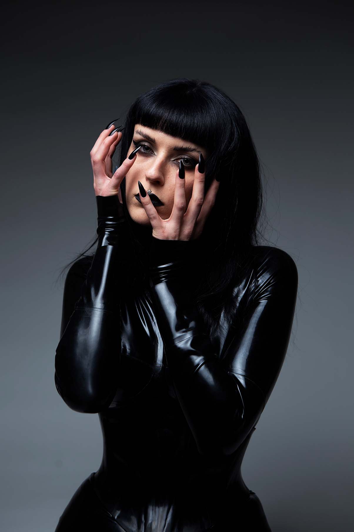 Press PR photography of musician Harpy dressed in black latex with long sharp black nails 