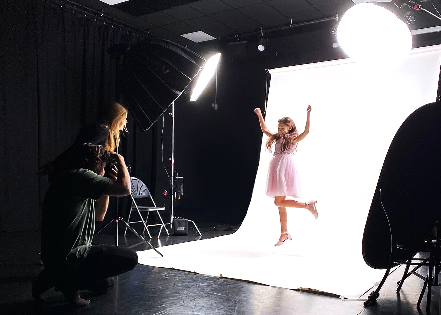 Young model in pink dress jumps as photographer takes a photo
