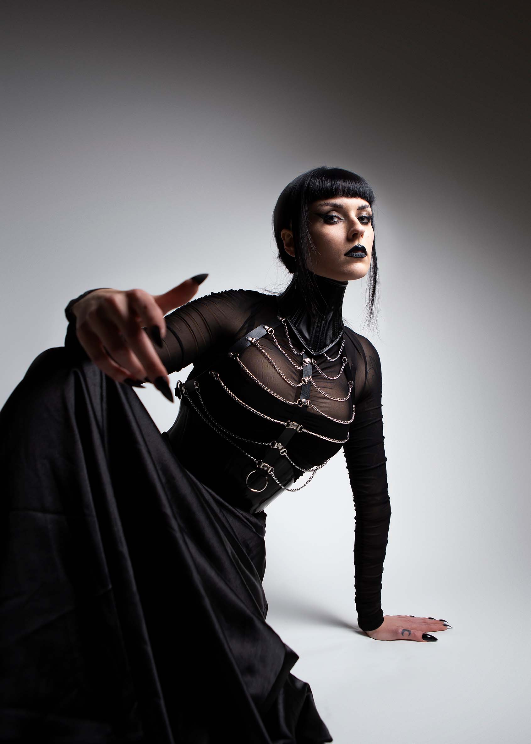 Editorial photography of musician Harpy, draped in black fabric and chains