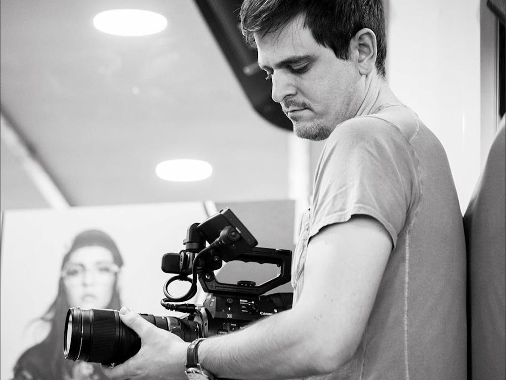 Black and white image of a camera man filming on video camera