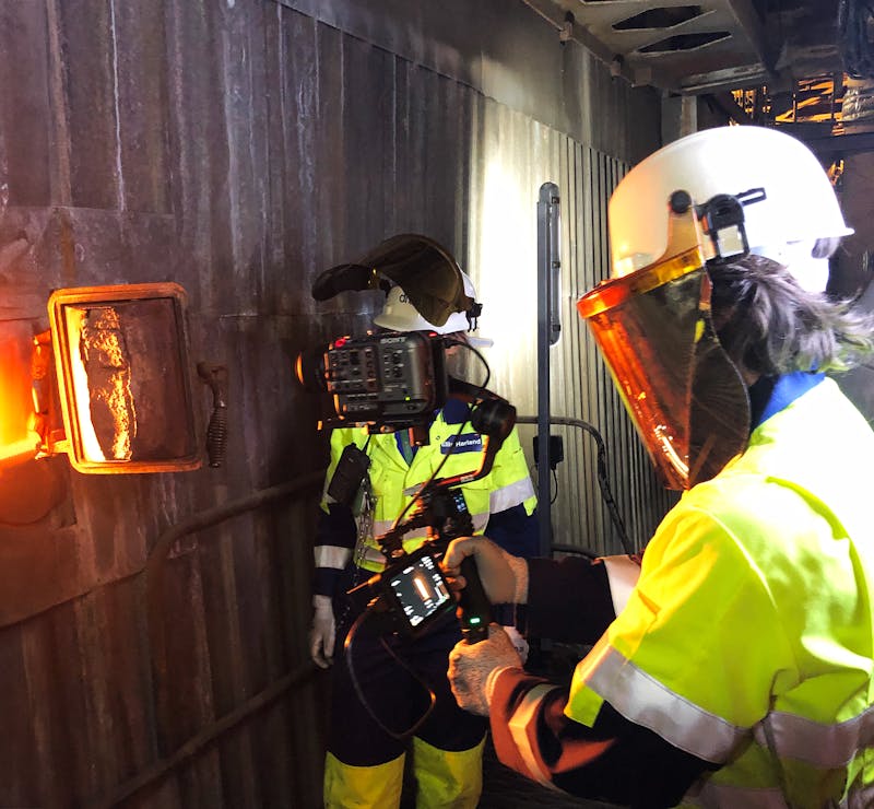 a cameraman film inside a hatch of an industrial boiler