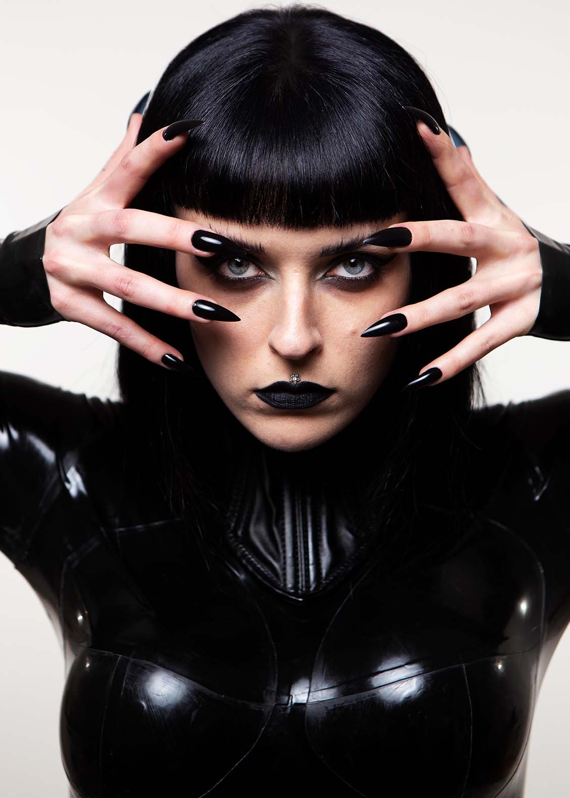 Press PR photography of musician Harpy dressed in black latex with long sharp black nails 