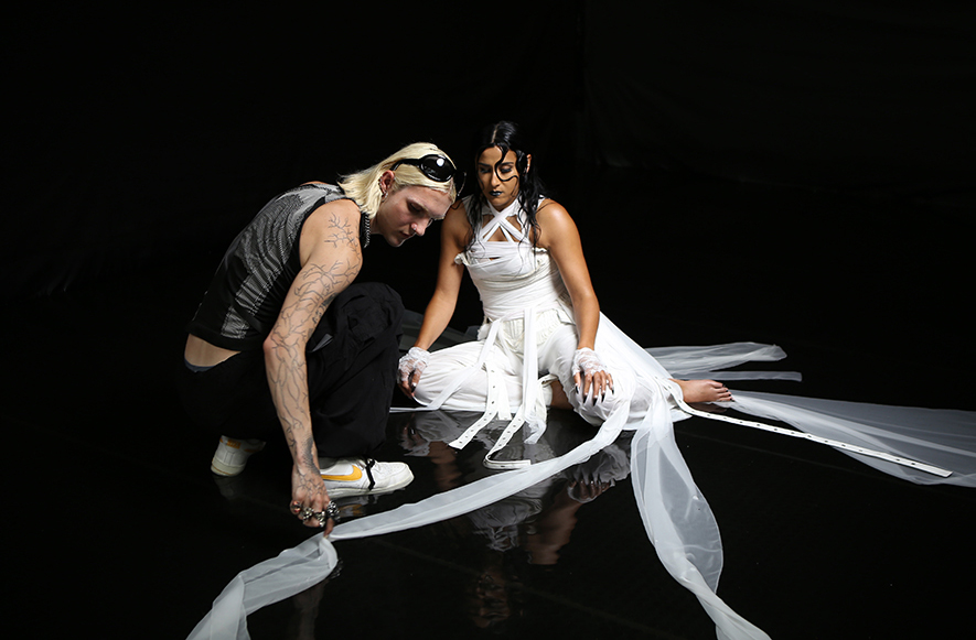 Clothing stylist behind the scenes touching up fabric on model 